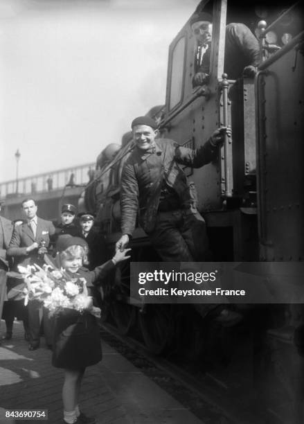 Petite fille avec un bouquet de fleurs saluant un cheminot, à Paris, France, avril 1936.