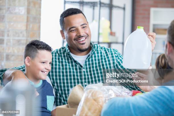 mixed race father and son donate items during food drive - emergency preparation stock pictures, royalty-free photos & images