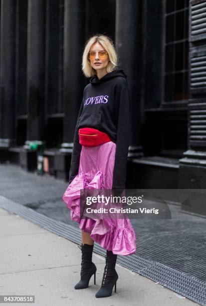 Lisa Hahnbueck wearing a black hoody with the print lovers, red Gucci velvet belt bag, pink ruffled skirt with slit, black ankle boots, vogue eyewear...