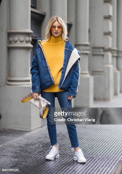 Lisa Hahnbueck wearing denim jacket, yellow knit, Fendi bag, denim jeans, white sneakers on September 6, 2017 in New York City.