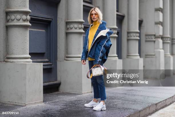 Lisa Hahnbueck wearing denim jacket, yellow knit, Fendi bag, denim jeans, white sneakers on September 6, 2017 in New York City.