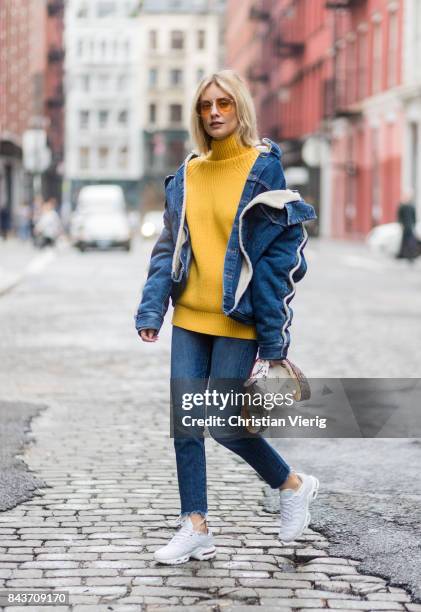 Lisa Hahnbueck wearing denim jacket, yellow knit, Fendi bag, denim jeans, white sneakers on September 6, 2017 in New York City.