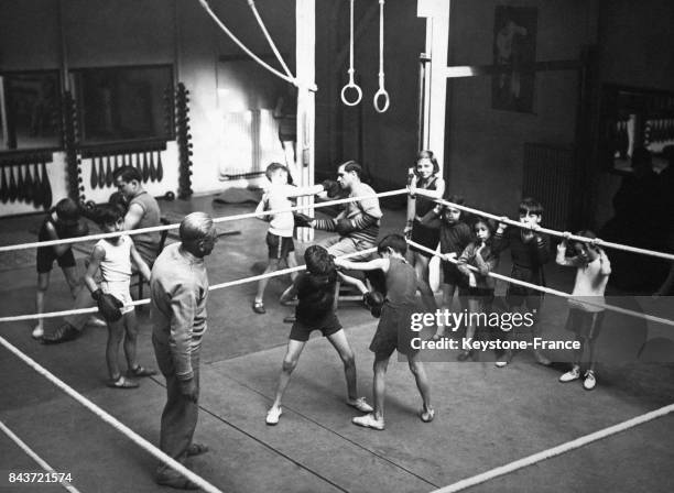 De jeunes garçons s'entraînent à la boxe sous l'oeil attentif de leur professeur, en France.