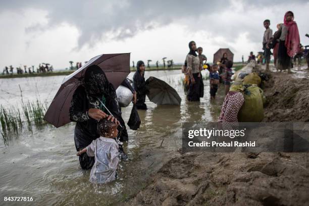 Rohingya woman, who fled from recent violence in Myanmar, takes bath her child in the flooded water after crossing the Bangladesh-Myanmar border in...