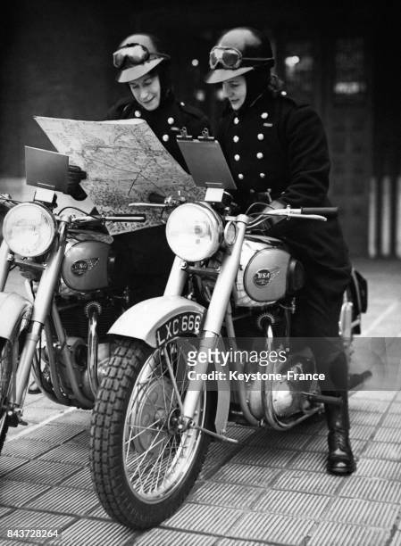 Deux femmes pompiers sur leurs motos regardent la carte routière avant leur départ pour une campagne de recrutement de pompiers volontaires, à...