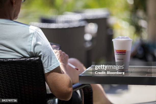 Cup of coffee sits next to a customer outside a Dunkin' Donuts Inc. Location in Los Angeles, California, U.S., on Wednesday, Sept. 6, 2017. Dunkin'...