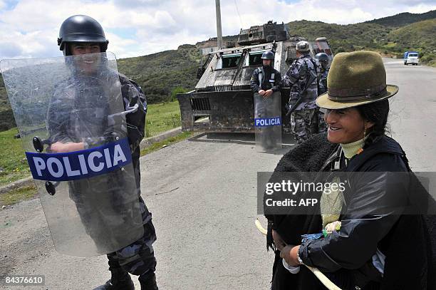 An indigenous woman smiles next to a riot policeman in the Cuenca-Loja highway, 450 km south of Quito, on January 20 during a protest against...