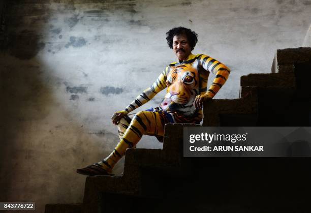 An Indian performer poses for a picture with his body painted as a tiger ahead of the 'Pulikali', or Tiger dance, in Thrissur on September 7, 2017....