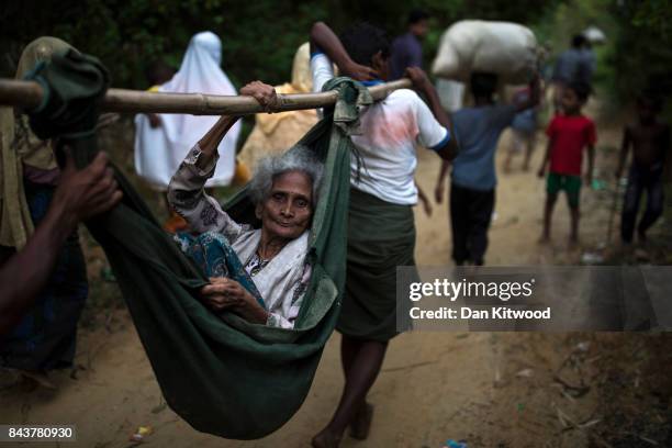 Rohingya Muslim refugees carry an elderly woman to a settlement, after crossing the Myanmar Bangladesh border on September 07, 2017 in Balukhali...