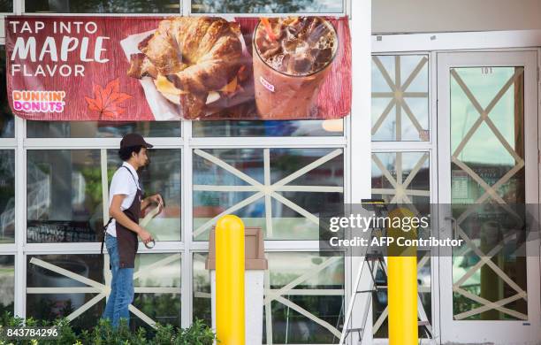 Worker puts tape on windows at a Dunkin Donuts store during preparations for Hurricane Irma in Miami, Florida, September 7, 2017. Miami orders people...