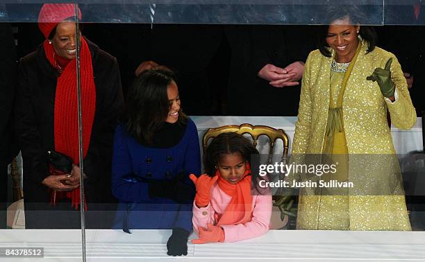 First Lady Michelle Obama gestures while watching the Inaugural Parade from the reviewing stand in front of The White House with daughters Sasha and...