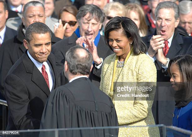President Barack Obama, with first lady Michelle Obama at his side, shakes hands with Chief Justice John G. Roberts Jr. After taking the oath of...