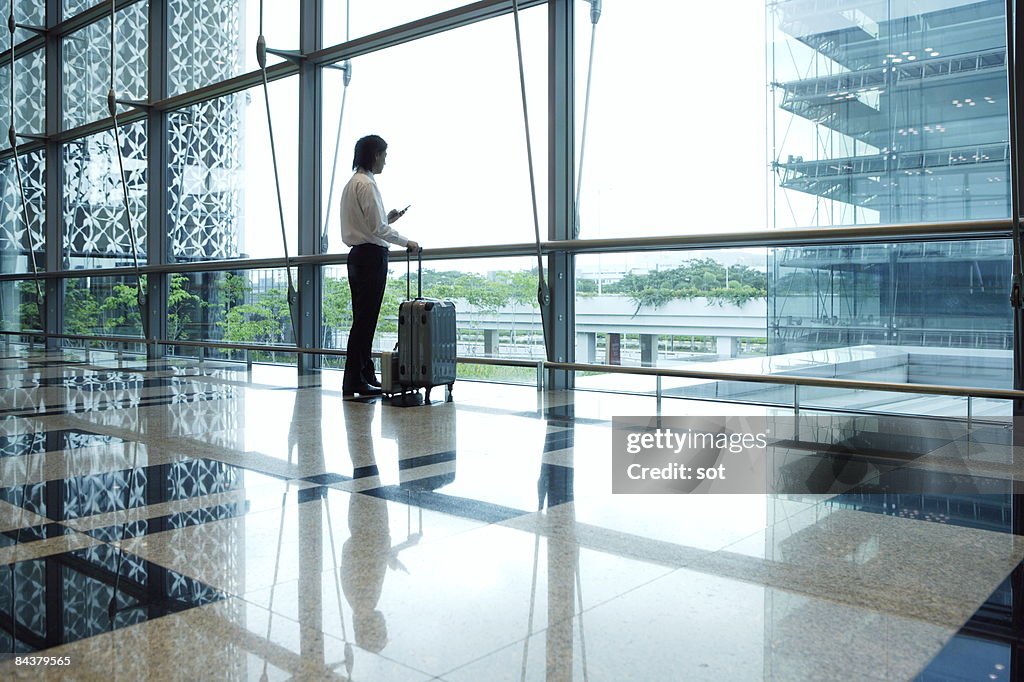 Businessman standing in airport using PDA