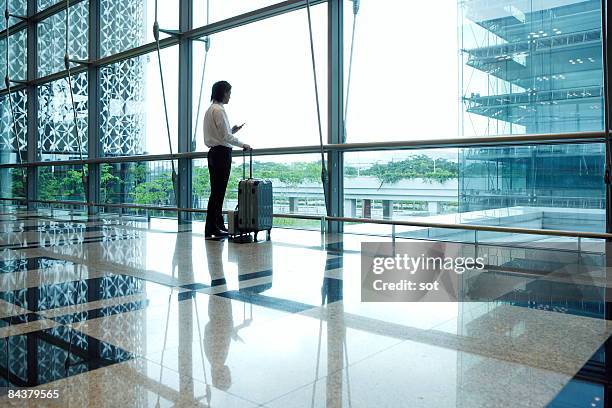 businessman standing in airport using pda - singapore airport stock pictures, royalty-free photos & images