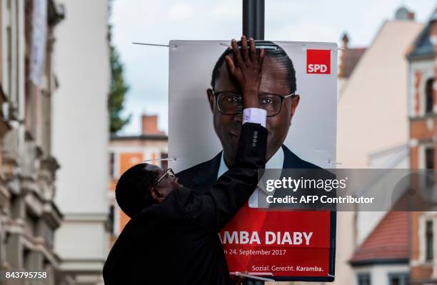 Senegalese-born German MP for the Social Democratic Party Karamba Diaby puts up a campaign poster in Halle on September 6, 2017. Diaby will be...