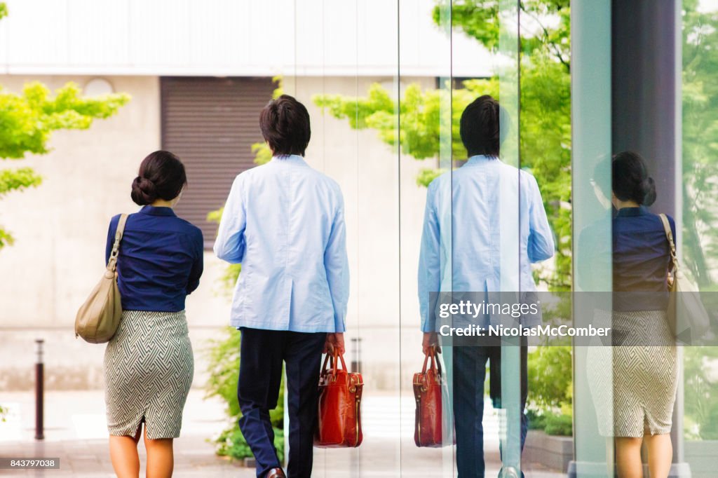 Two Japanese business people walking side by side rear view