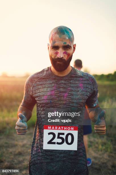 marathon racer mit holi farben - holirun stock-fotos und bilder