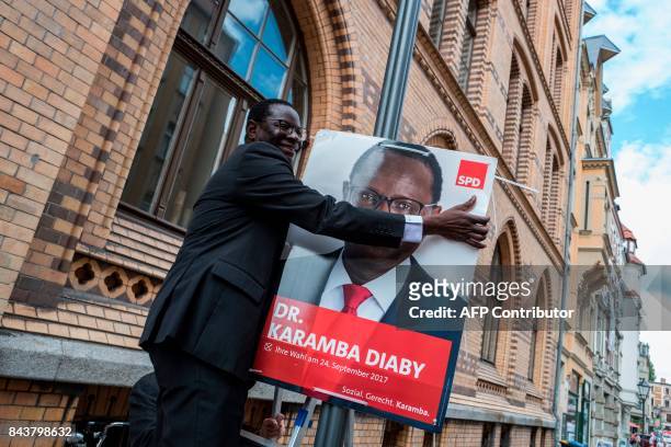 Senegalese-born German MP for the Social Democratic Party Karamba Diaby puts up a campaign poster in Halle on September 6, 2017. Diaby will be...