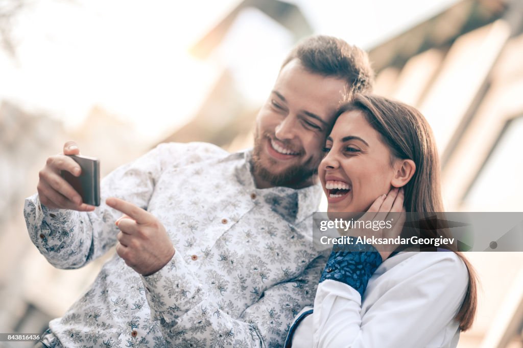 Young Attractive Couple with Smartphone Smiling at City Street