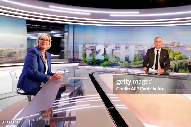 French far-right Front National party president and member of parliament Marine Le Pen and French television presenter Gilles Bouleau look on before...