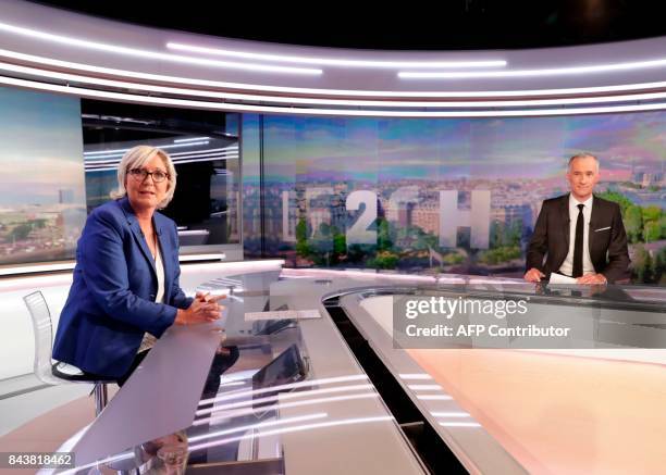 French far-right Front National party president and member of parliament Marine Le Pen and French television presenter Gilles Bouleau look on before...