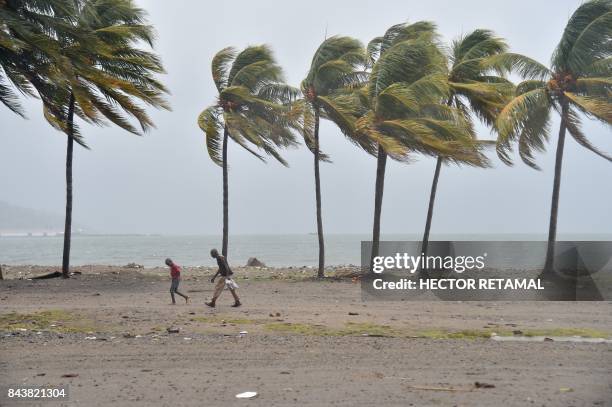 Haitian people walk through the wind and rain on a beach, in Cap-Haitien on September 7 as Hurricane Irma approaches. Irma was packing maximum...