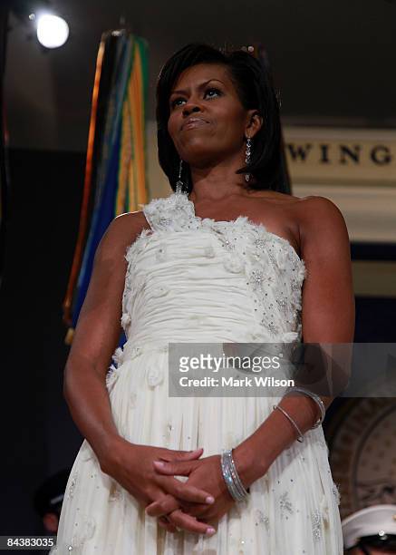 First Lady Michelle Obama stands by as her husband speaks on stage during MTV & ServiceNation: Live From The Youth Inaugural Ball at the Hilton...