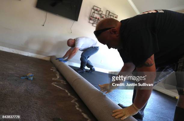 Mike Praslicka rolls up a wet carpet with Justin Davison in his flood damaged home on September 7, 2017 in Richwood, Texas. Over a week after...