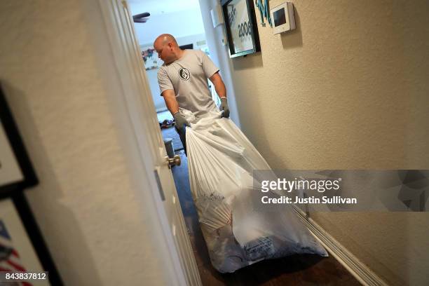 Justin Davison pulls a trash bag full of flood damaged as he helps a friend clean out his flooded home on September 7, 2017 in Richwood, Texas. Over...