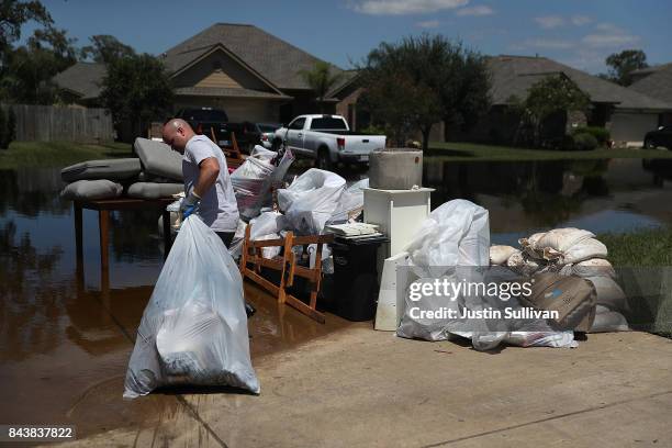 Justin Davison pulls a trash bag full of flood damaged items to a trash pile as he helps a friend clean out his flooded home on September 7, 2017 in...