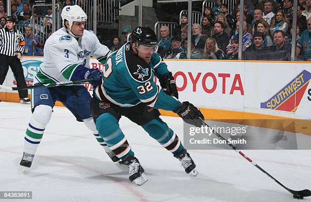Kevin Bieksa of the Vancouver Canucks tries to stop Claude Lemieux of the San Jose Sharks who maneuvers the puck down the ice during an NHL game on...