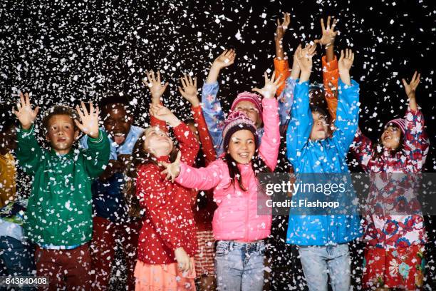 group of children dressed in winter coats having fun in the snow - abrigo de colores fotografías e imágenes de stock