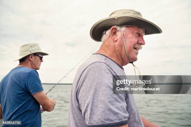 actives seniors brothers with hats on a fishing boat. - old brother stock pictures, royalty-free photos & images