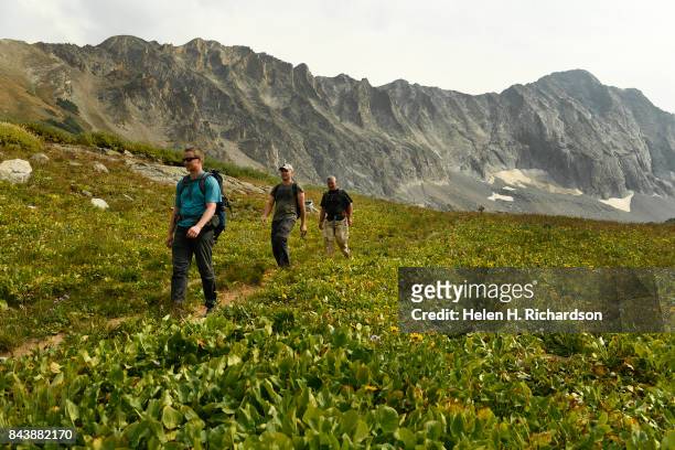Hikers David Bossert, front, George Nick, middle and Jesse Hansen, in back, head down the trail from Capitol Lake with the massive Capitol Peak...
