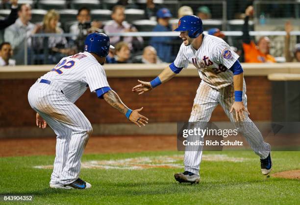 Dominic Smith and Kevin Plawecki of the New York Mets congratulate each other after scoring on a double by Jose Reyes against the Cincinnati Reds...