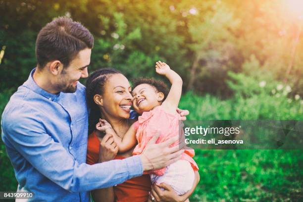 familie wandern im feld tragen junge baby girl - person gemischter abstammung stock-fotos und bilder
