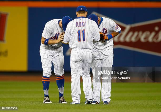 Outfielders Brandon Nimmo and Juan Lagares bow to Norichika Aoki of the New York Mets after defeating the Cincinnati Reds 7-2 during a game at Citi...