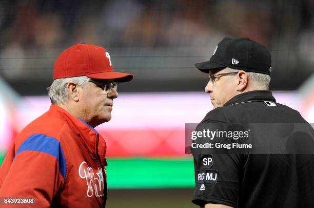 Pete Mackanin of the Philadelphia Phillies talks with home plate umpire Paul Emmel during the sixth inning of the game against the Washington...