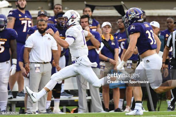 Quarterback Bryan Schor of the James Madison Dukes runs away from linebacker Cannon Gibbs of the East Carolina Pirates during a game between the...