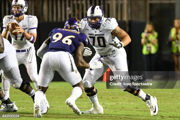 Offensive lineman Aaron Stinnie of the James Madison Dukes blocks defensive end Kiante Anderson of the East Carolina Pirates during a game between...