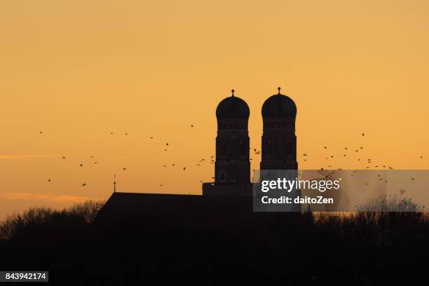 silhouette of bell towers of munich cathedral frauenkirche with birds flying by, munich, bavaria, germany - silhouette münchen stock pictures, royalty-free photos & images