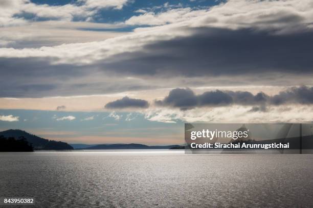 ethereal scenery of land beyond the sea under moody sky - bruny island stock pictures, royalty-free photos & images