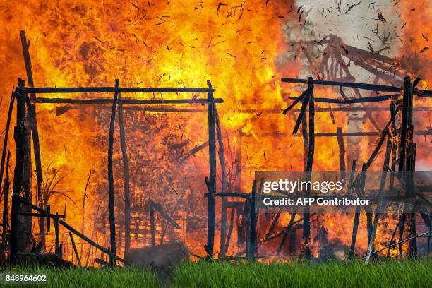 In this photograph taken on September 7 a house is engulfed by fire in Gawdu Tharya village near Maungdaw in Rakhine state in northern Myanmar. The...