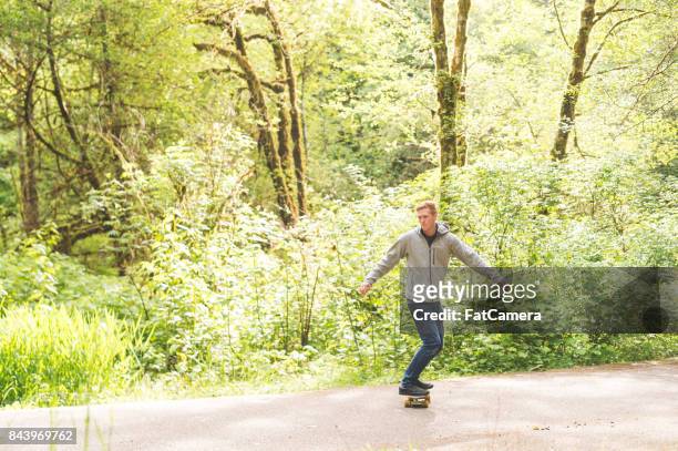 rothaarige männliche skateboards durch wald - confidence male landscape stock-fotos und bilder