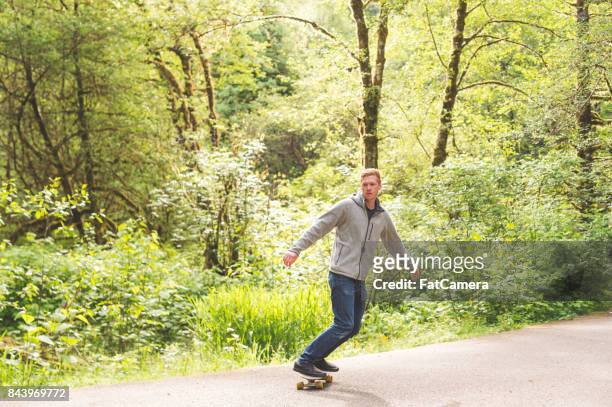 rothaarige männliche skateboards durch wald - confidence male landscape stock-fotos und bilder