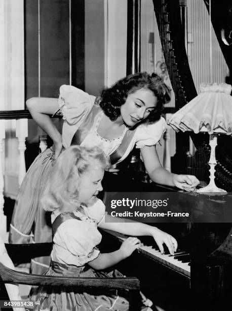 Joan Crawford aidant sa fille Christina lors de sa leçon de piano, aux Etats-Unis, le 25 juillet 1947.