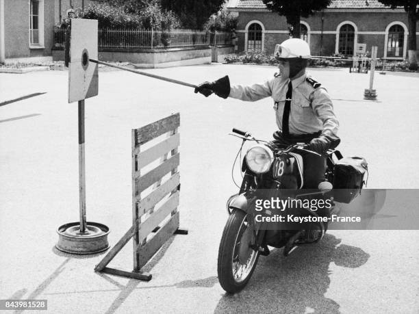 Exercice d'équilibre sur moto dans lequel le gendarme doit place l'extrémité du bâton dans le cercle lors de la formation des gendarmes à moto sur...