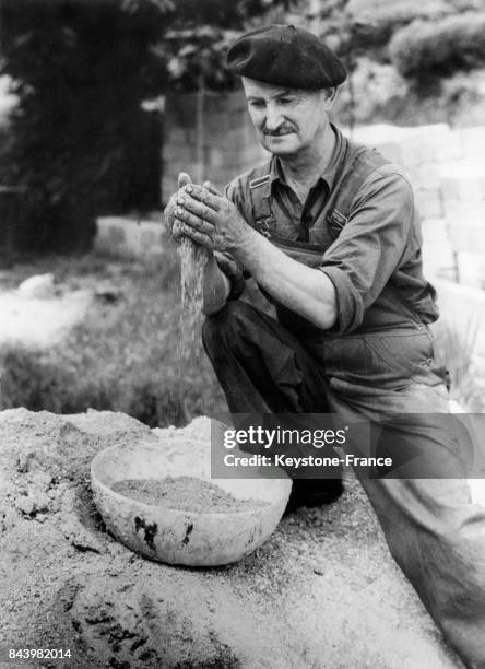 Elie Teissonnière faisant couler entre ses doigts du sable aurifère découvert dans un puits près du Vigan dans les Cévennes en France, en 1953.