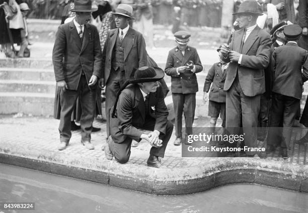 Des pélèrins boivent et se lavent les mains à l'eau de la fontaine miraculeuse en 1932 à Sainte-Anne d'Auray, France.
