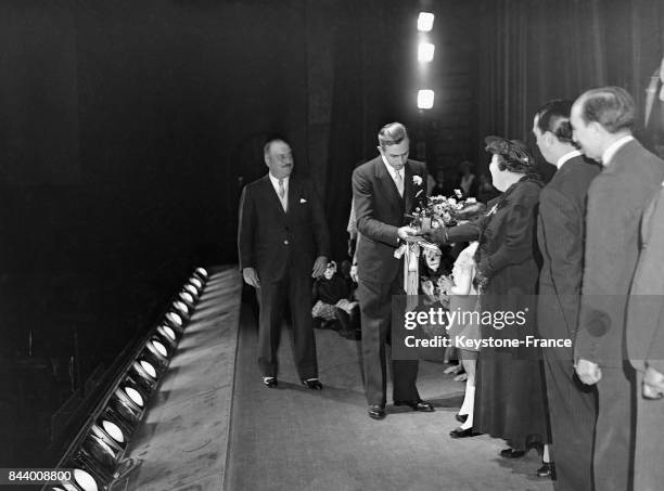 Dans la salle du cinéma Gaumont-Palace, Walt Disney reçoit un bouquet de fleurs et la médaille d'or du CIDAL , à Paris, France en 1935.
